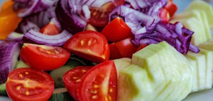 Colorful summer vegetable salad featuring tomatoes, cucumbers, and red onion slices on a plate.
