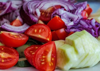 Colorful summer vegetable salad featuring tomatoes, cucumbers, and red onion slices on a plate.